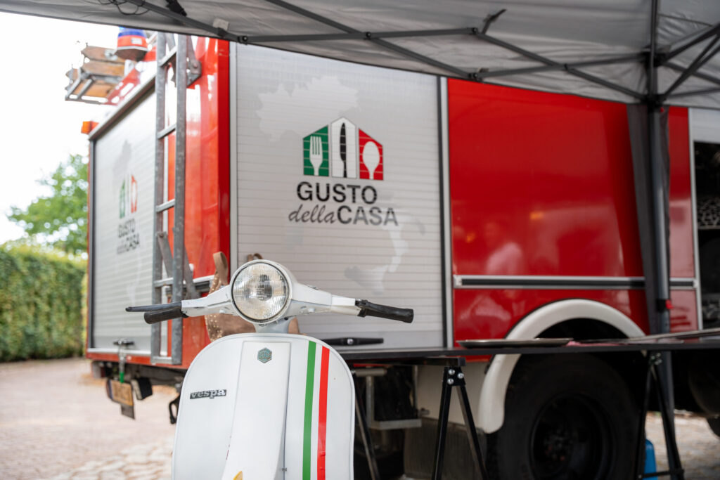 De foodtruck van Gusto Della Casa in Italiaanse stijl met een Vespa ervoor